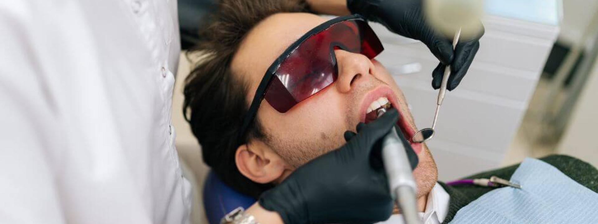 Man at dentist using laser for procedure.
